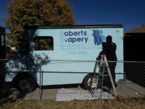 Mobile Bike Shop Repair Van restoration "before" picture of light blue van with "Roberts Drapery" logo